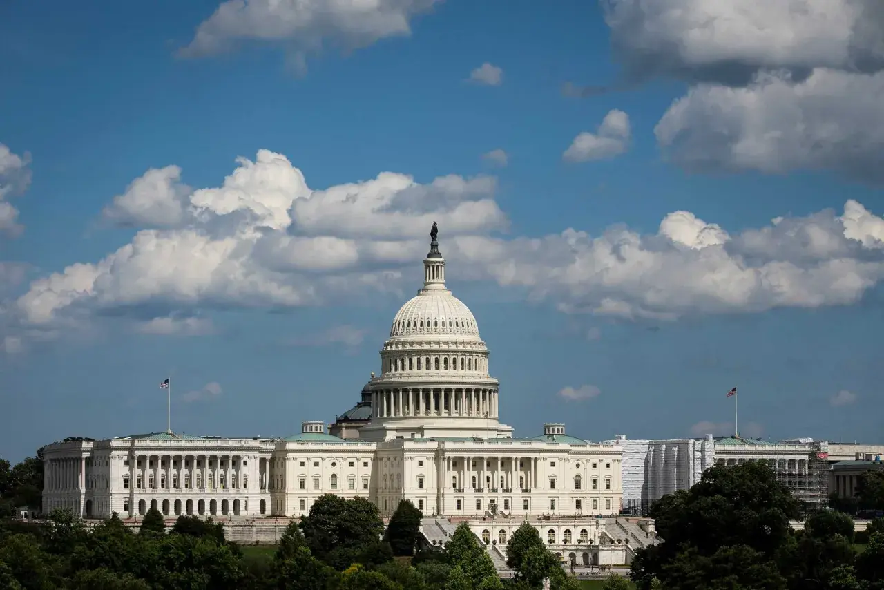The U.S. Capitol building under a cloudy sky. Members of Congress work within these walls, but do members of Congress have security clearances?