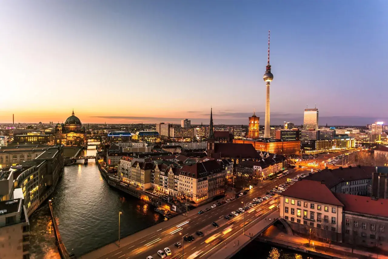 Berlin vid solnedgången. En bro leder över floden, med bilar som susar förbi. En fantastisk utsikt över Tyskland, som kan vara en del av en resa från Danmark.