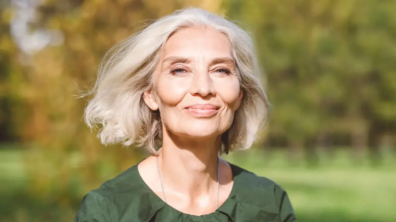 Mujer sonriente con cabello rubio platino, ideal para matizar canas. Su piel irradia luz natural.