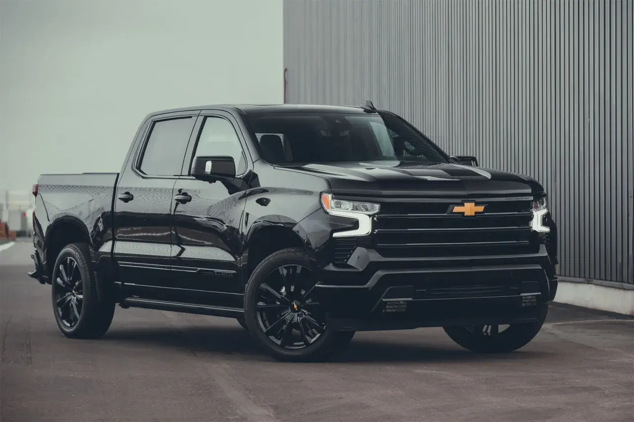 Svart Chevrolet Silverado High Country, en av många imponerande Chevrolet modeller, parkerad framför en modern byggnad.