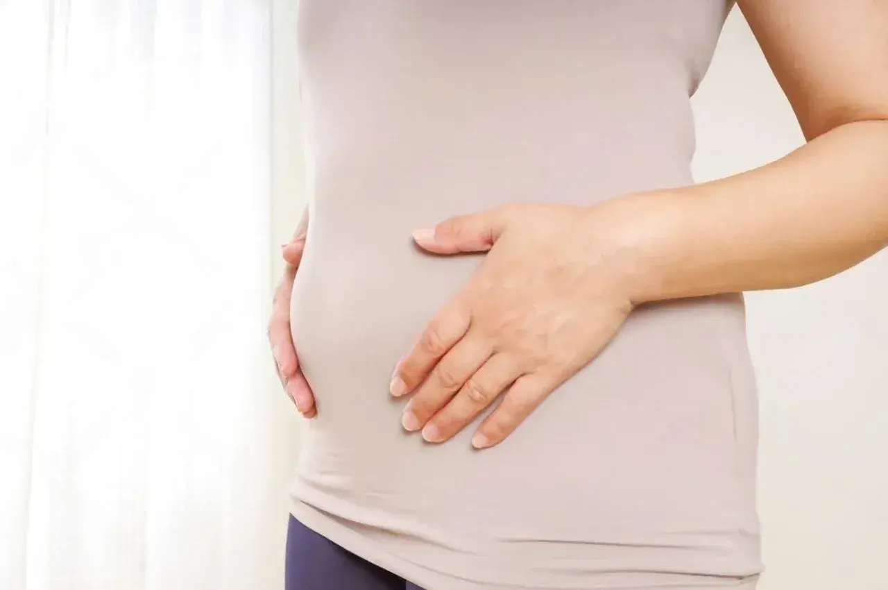 Mujer tocando su abdomen, buscando soluciones para quitar barriga menopausia.