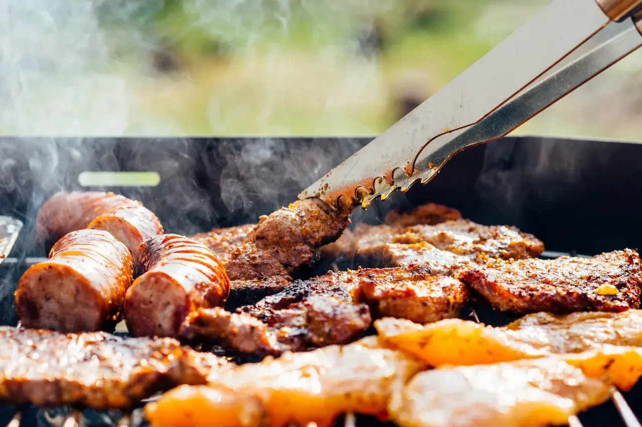 Des saucisses et des morceaux de viande au barbecue, fumants et grillés à la perfection. Un délice estival.