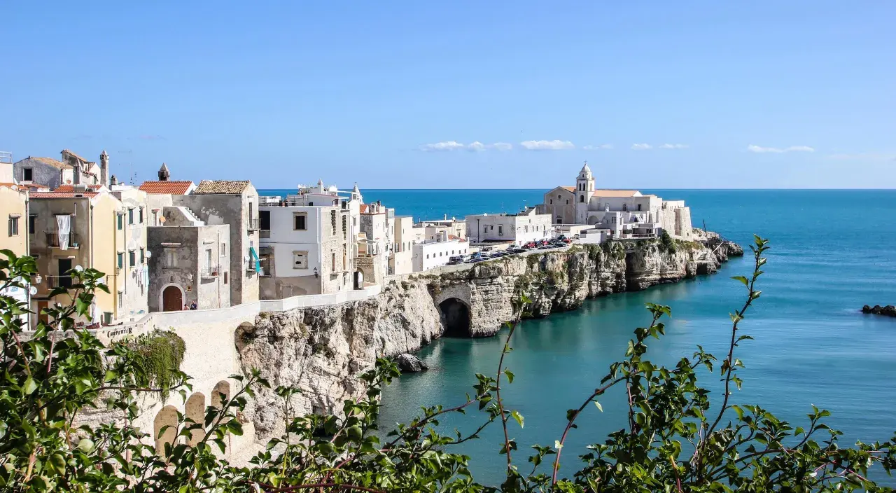 A picturesque coastal town in southern Italy, perfect for a southern Italy itinerary. White buildings cling to cliffs overlooking the turquoise sea.