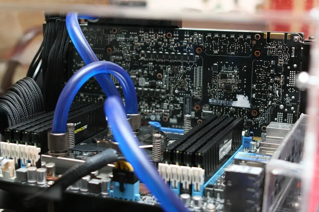 Composants d'un PC, dont des tubes bleus de watercooling et des barrettes de RAM. Utile pour connaître sa carte mère Windows 10.