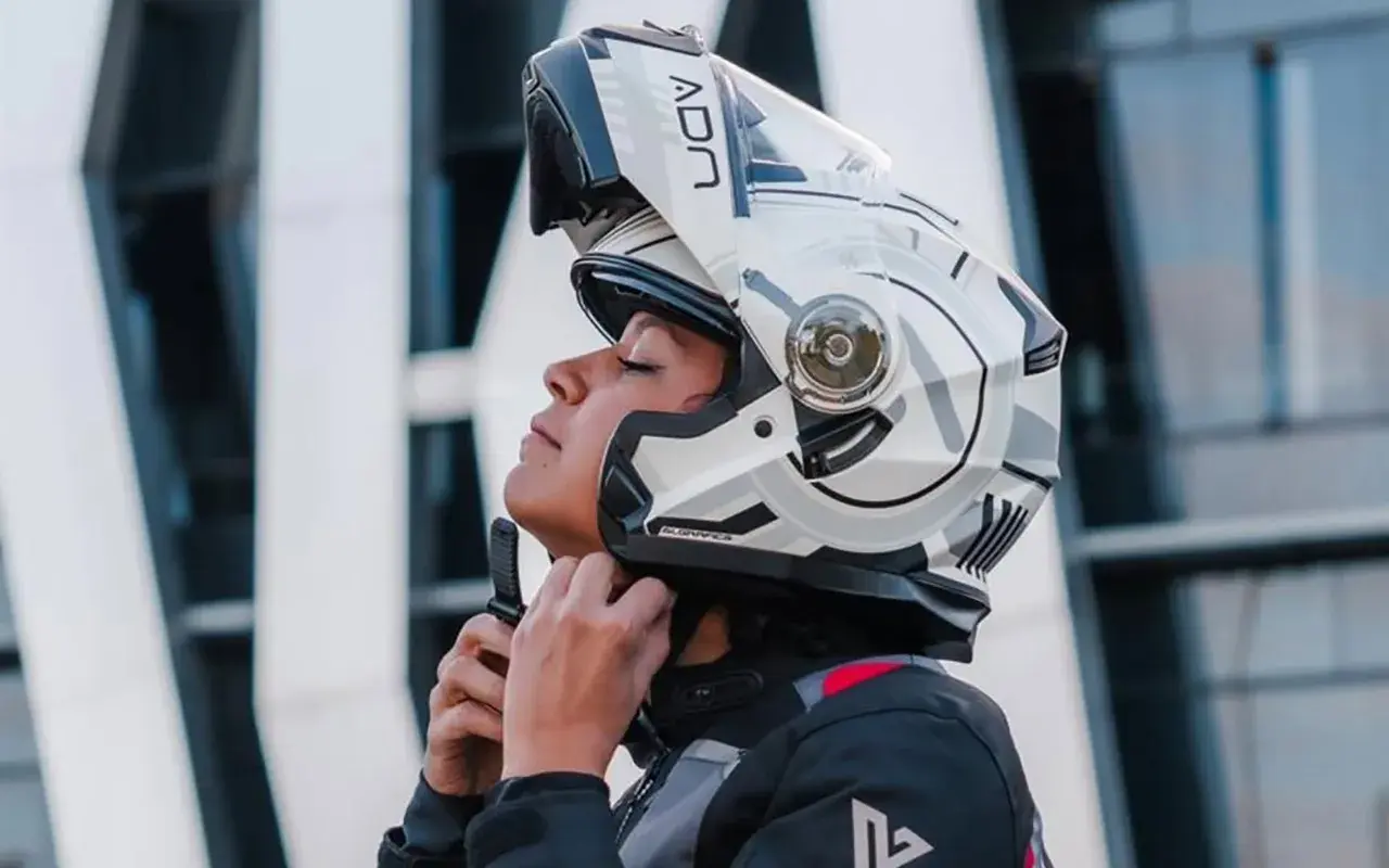 Mujer ajustando su casco integral o modular, listo para la aventura.