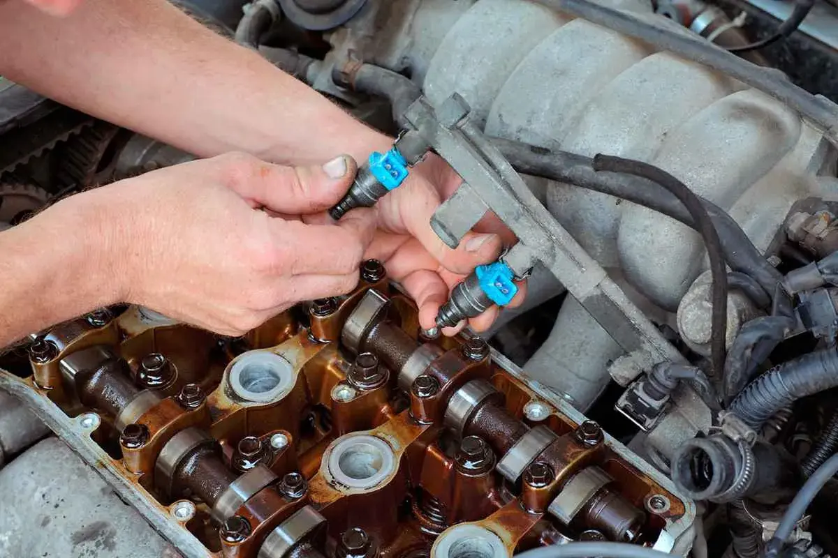 Mecánico instala inyectores de combustible en un motor. Aunque se puede circular con un inyector averiado, es mejor repararlo.