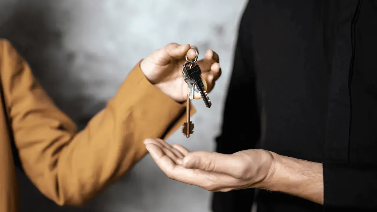 Mani che si scambiano chiavi, simbolo di un immobile in comproprietà abitato da un solo proprietario.