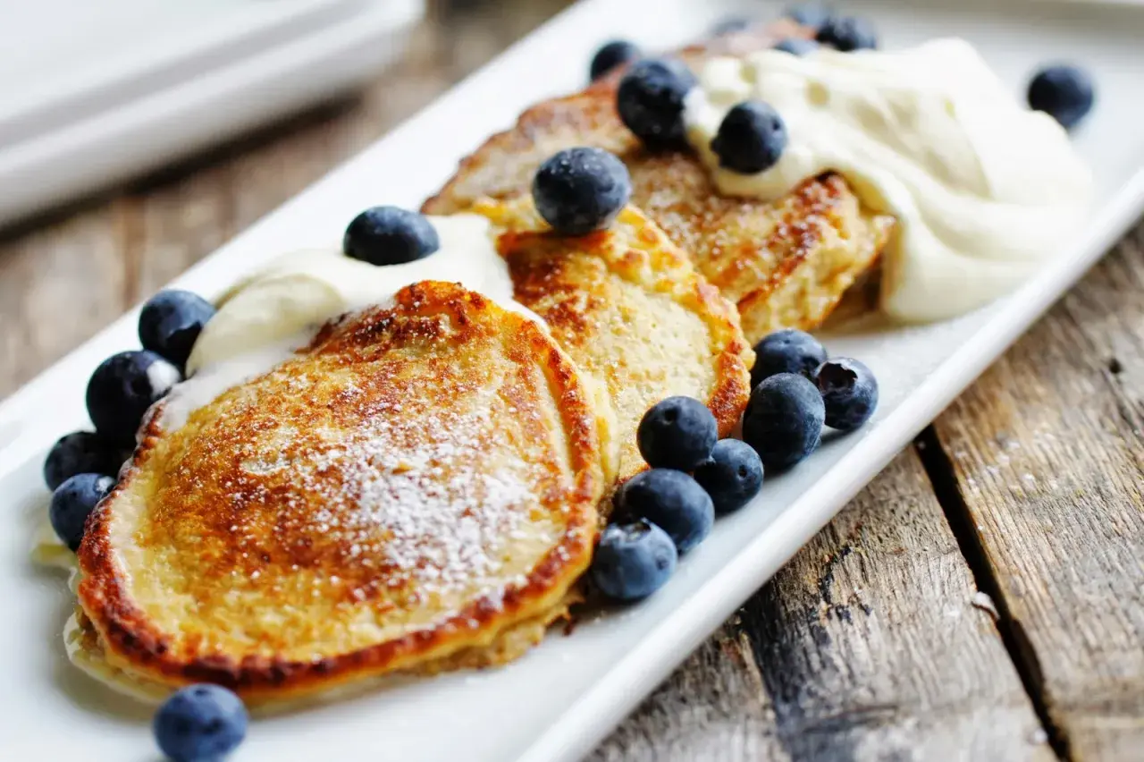 Gyllene pannkakor med havregryn, toppade med vispad grädde och färska blåbär. En härlig frukost eller fika.