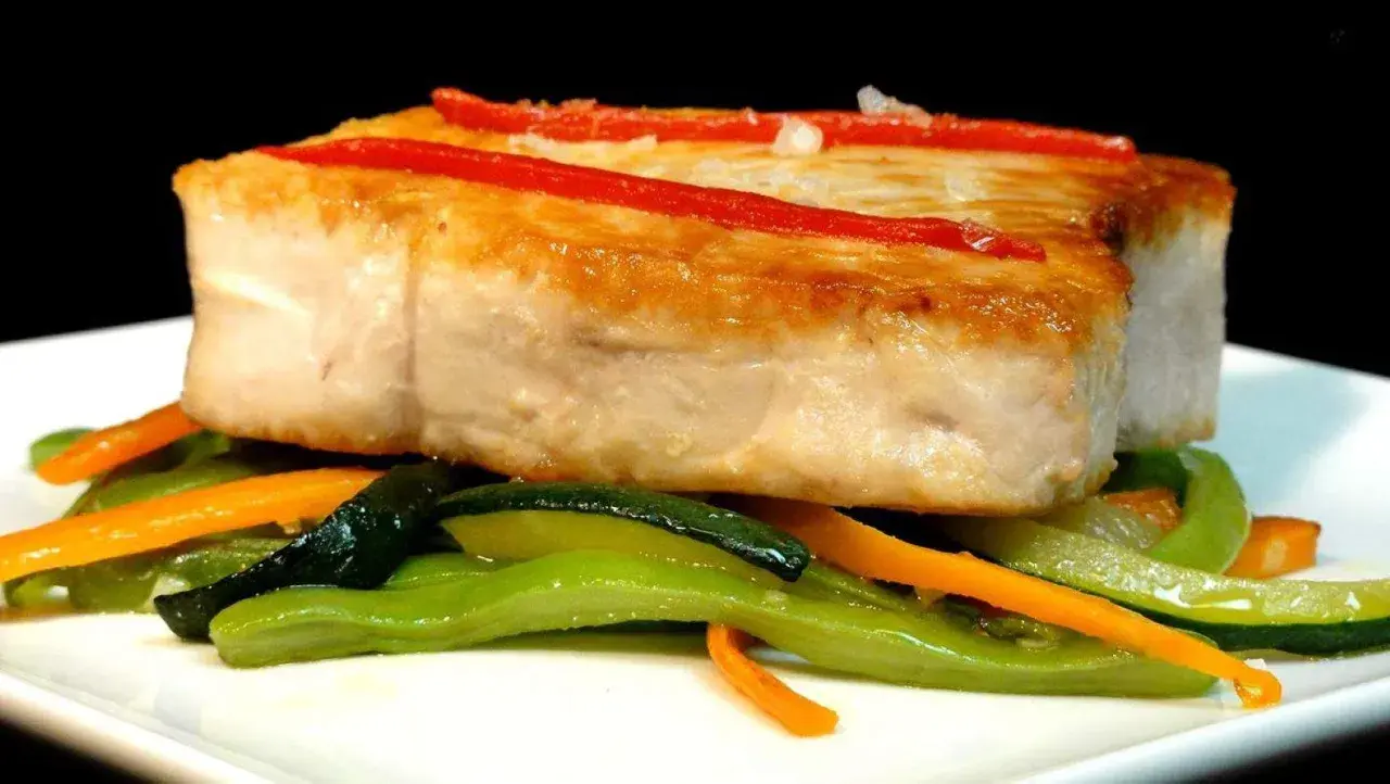 Bonito jugoso con pimientos rojos y verduras salteadas.