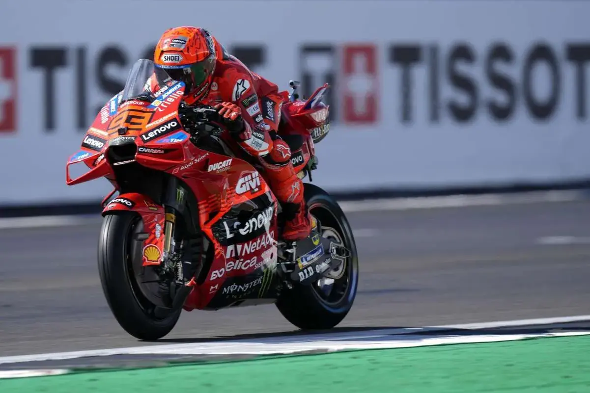 Piloto de Ducati en carrera, con su traje rojo y casco naranja. El número 23 es visible. Mar Márquez compite en la pista.