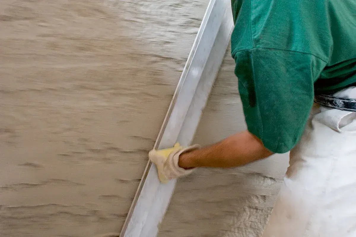 Hand mit Handschuh glättet feuchten Putz. Spezialputz gegen Feuchtigkeit schützt die Wand.