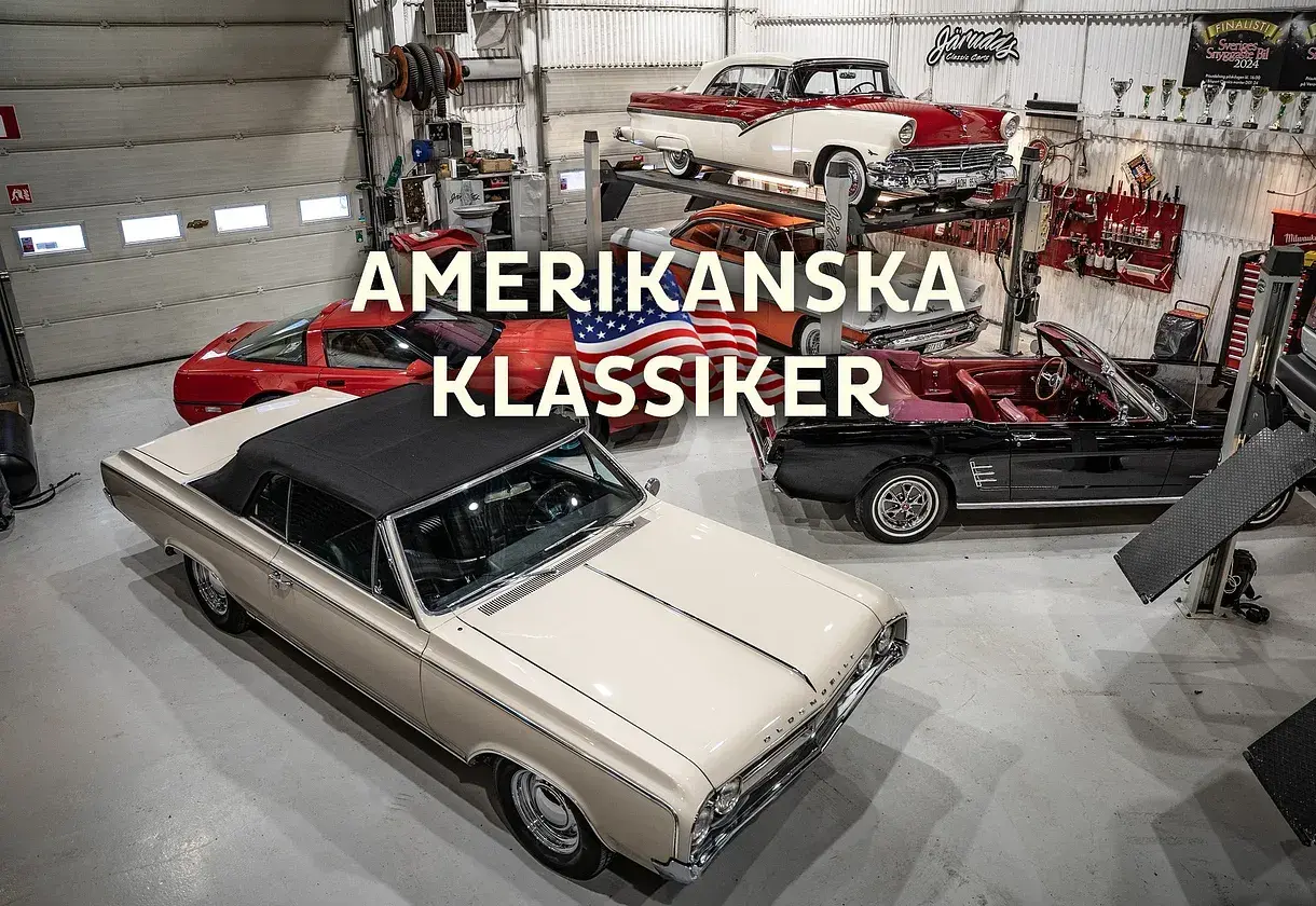 En samling amerikanska klassiker, inklusive 70 tals bilar, i ett garage. En beige cabriolet står i förgrunden.