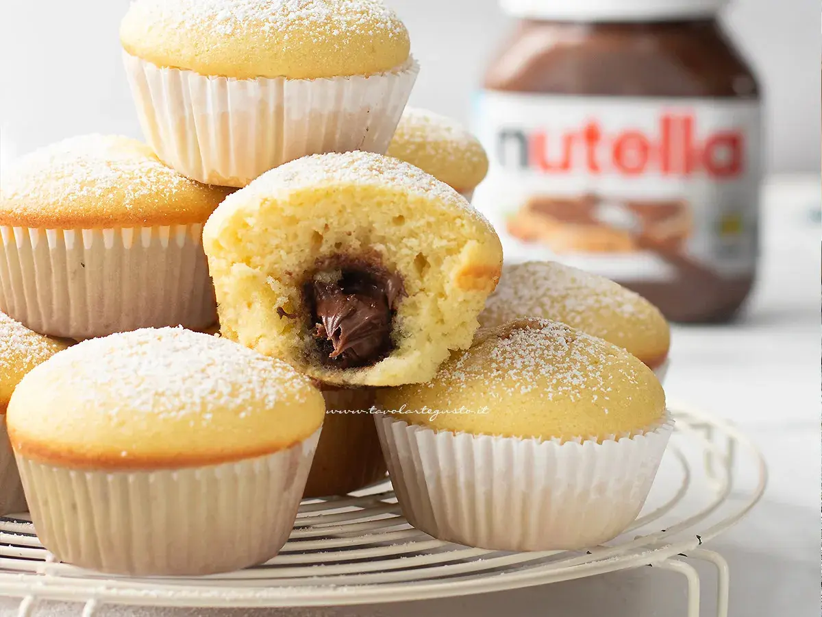 Muffin soffici con cuore di Nutella, perfetti per una ricetta muffin semplici e golosa. Spolverati di zucchero a velo.