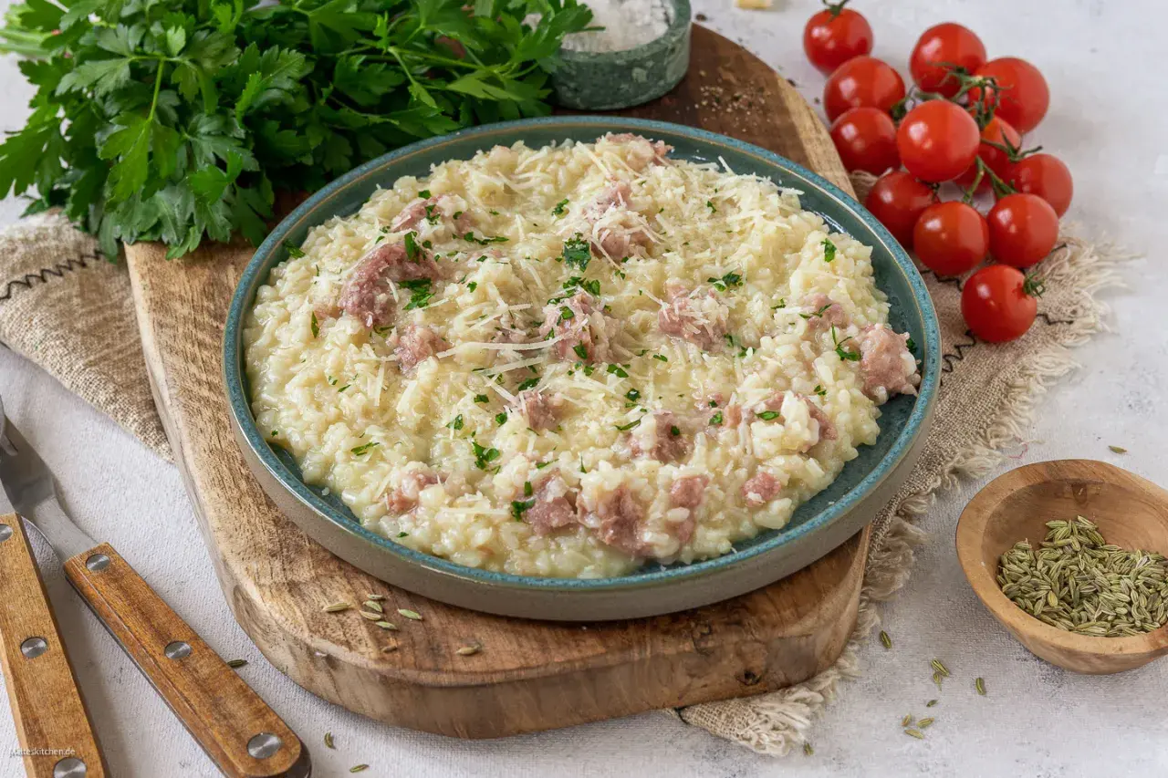 Cremiges Risotto mit Salsiccia, garniert mit Parmesan und Petersilie, serviert auf einem rustikalen Holzbrett.