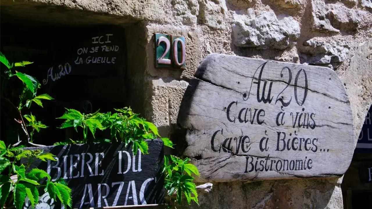 Bonjour! Drewniany szyld "Au 20" zaprasza do piwnicy z winami i piwami. Obok tablica z napisem "Biere du Arzac".