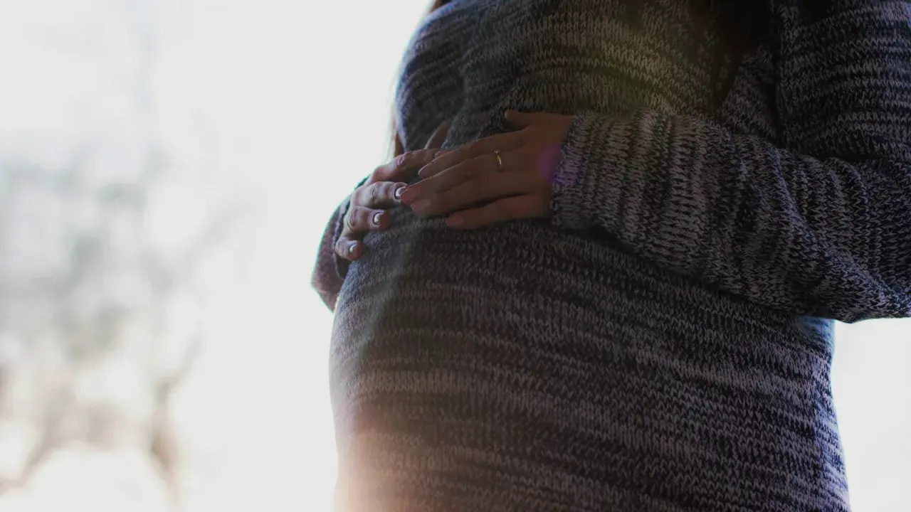 En kvinna med gravid mage, gravid efter 40, håller varsamt om sin mage.