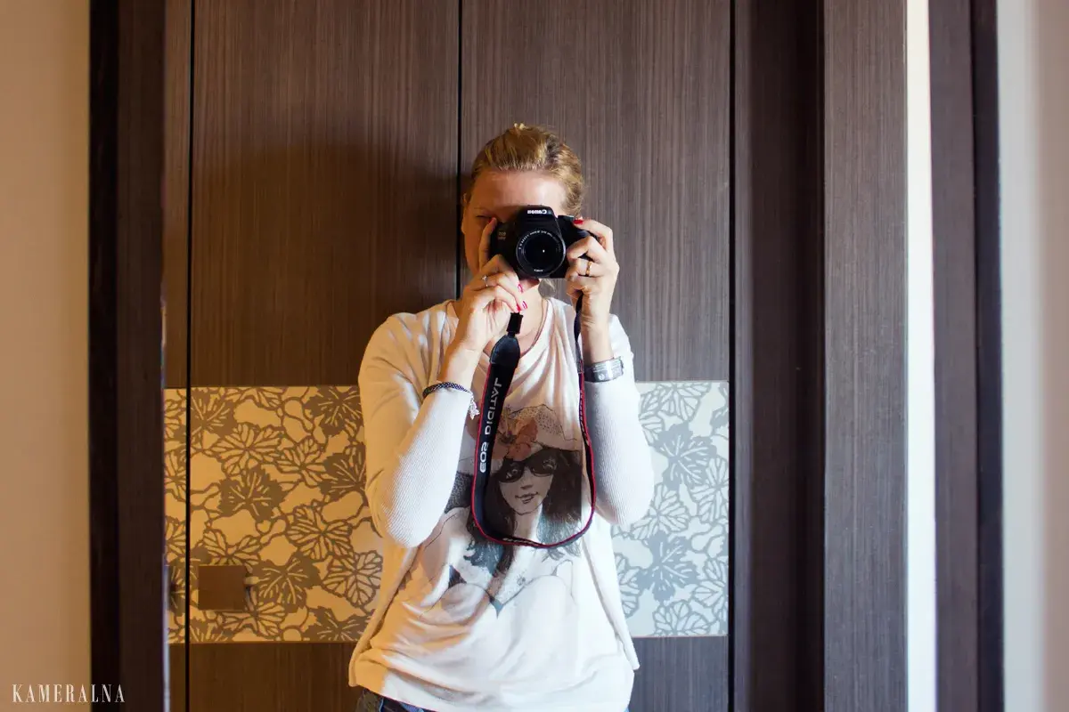 Dziewczyna z aparatem w rękach, ćwiczy na zajęciach szkoły fotografii.
