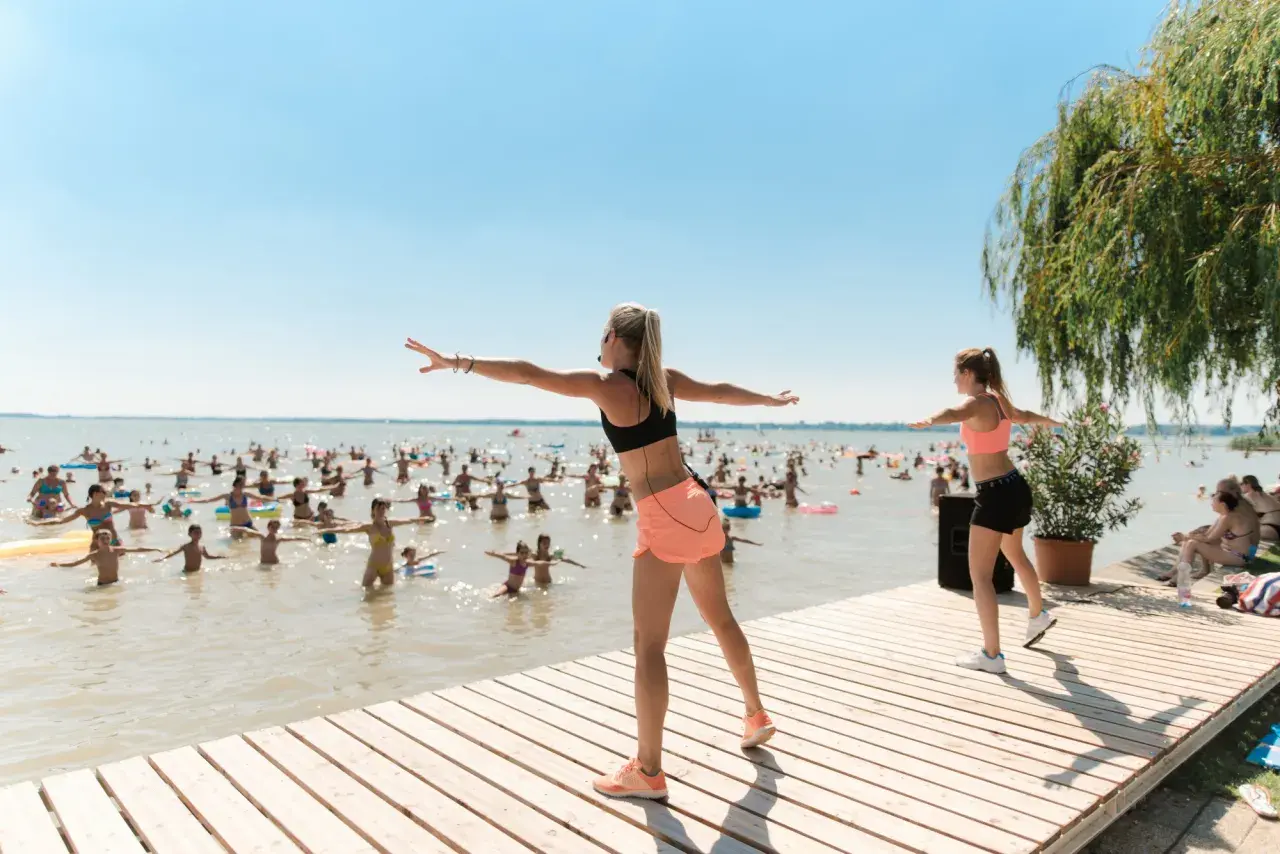 Fitnessgruppe am See in Hévíz, Ungarn. Trainerinnen leiten eine Wassergymnastik-Session für viele Teilnehmer im Wasser.