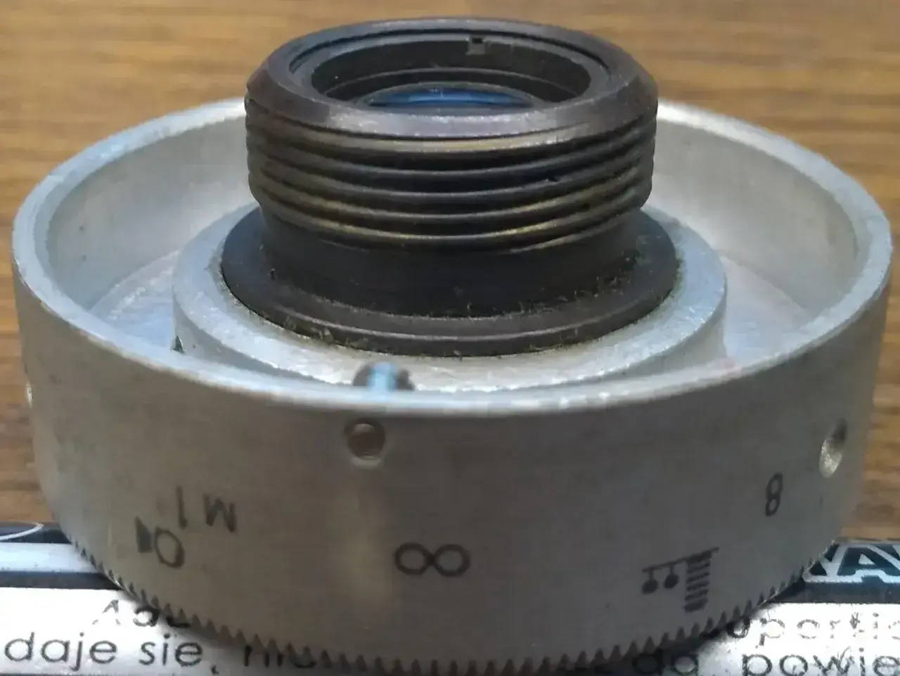 Metalowy pierścień z oznaczeniami od 1 do 8, nieskończoności i innymi symbolami, służący do regulacji obiektywu. Idealny do zoom test.