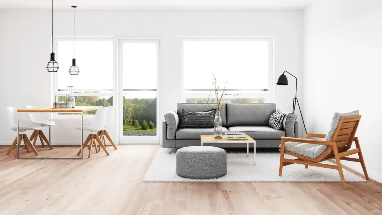 Elegante salón comedor con sofás grises, mesa de madera y sillas blancas. La iluminación se logra con lámparas colgantes y de pie, perfectas para combinar lamparas salon comedor.