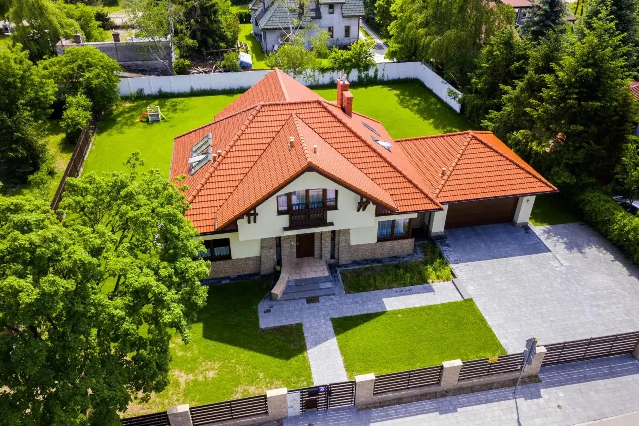 Piękny dom z czerwonym dachem i ogrodem. Zastanawiasz się, ile kosztuje projekt domu?