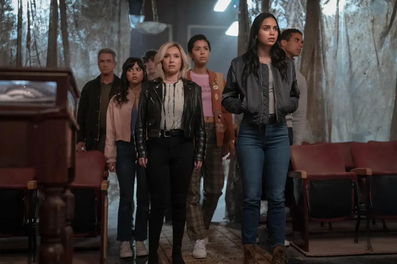 Grupa młodych ludzi, w tym Melissa Barrera i Jenna Ortega, stoi w przerażeniu. To krzyk 7 obsada, która właśnie odkryła coś strasznego.