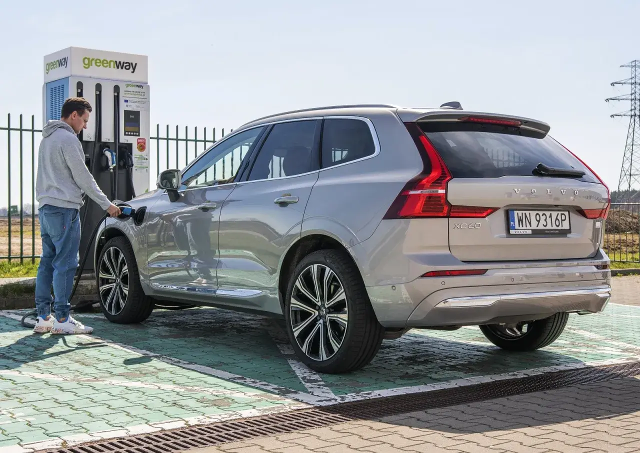 Mężczyzna ładuje Volvo XC60, nowoczesną turbo hybrydę, na stacji Greenway.