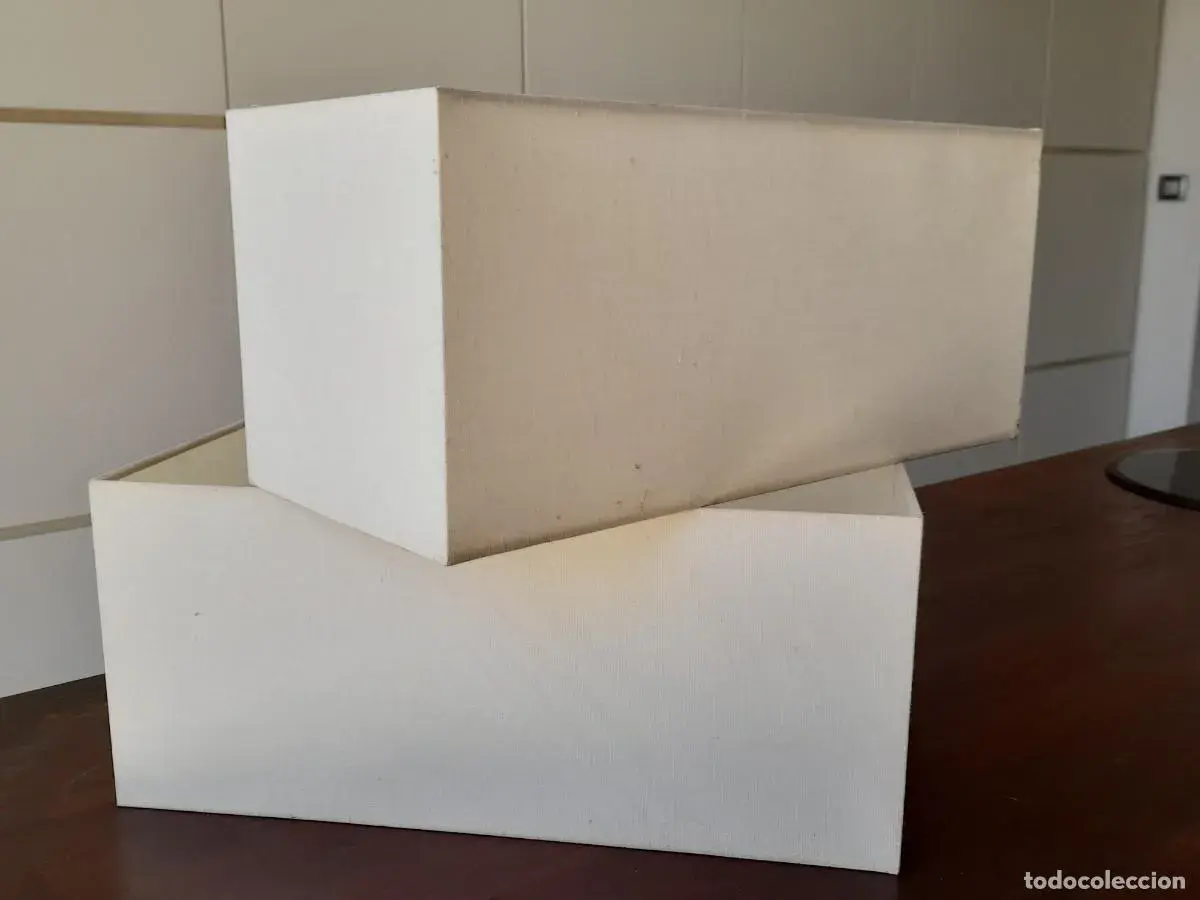 Dos pantallas de lámpara de pared apiladas, de tela blanca, listas para dar luz.