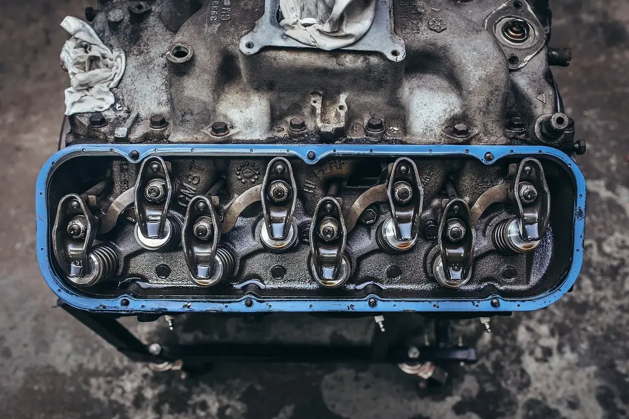 Detalle de balancines y resortes de un motor, con aceite visible, parte del sistema de lubricación.
