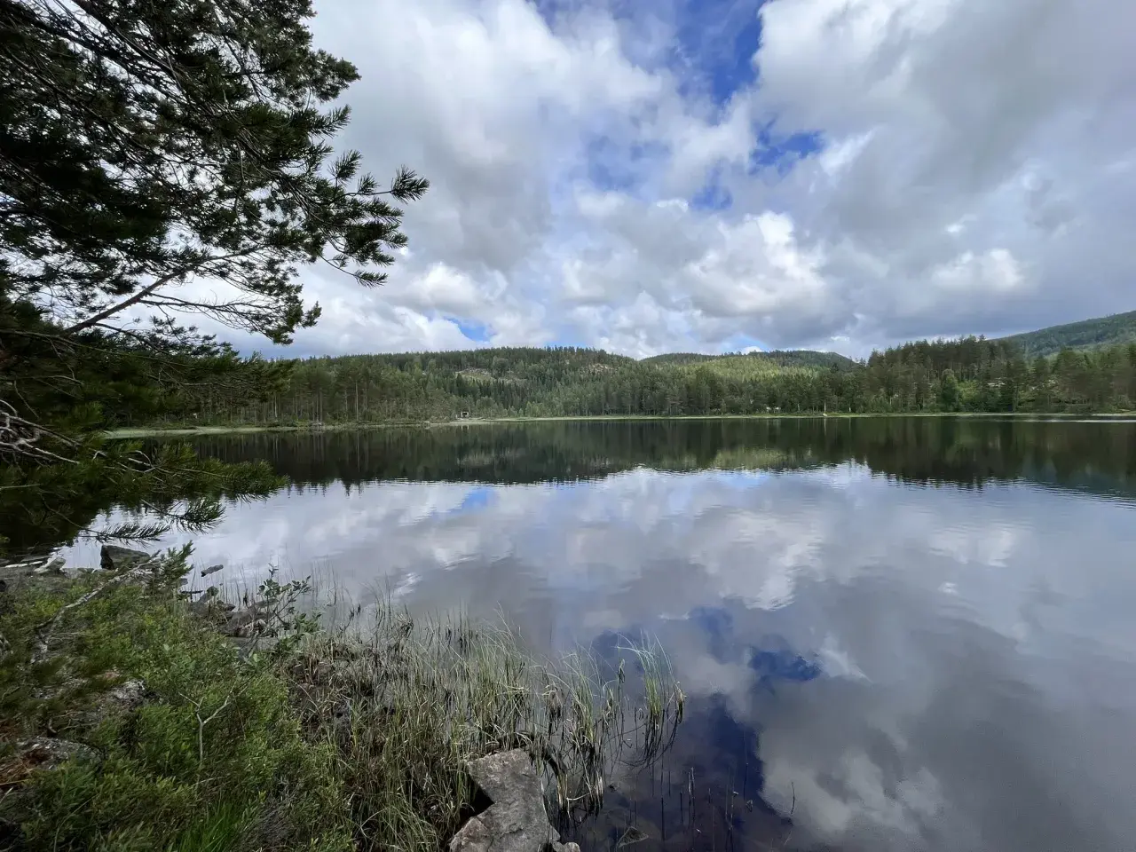 Spegelblank sjö med moln som reflekteras. Perfekt för en paus under cykelturen på cykelleder Sverige.