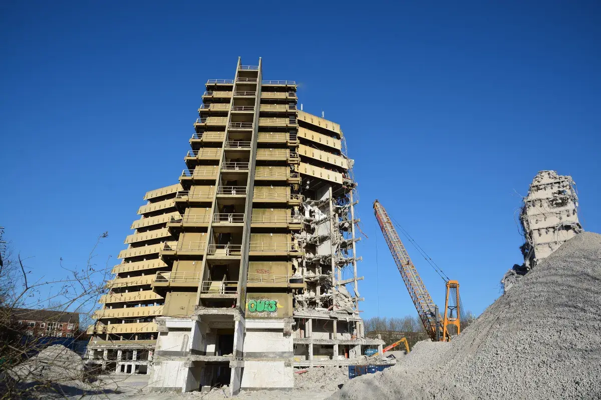 Abriss des "Affenfelsen" in Hamburg. Ein Kran demontiert das Hochhaus, daneben ein Trümmerberg.