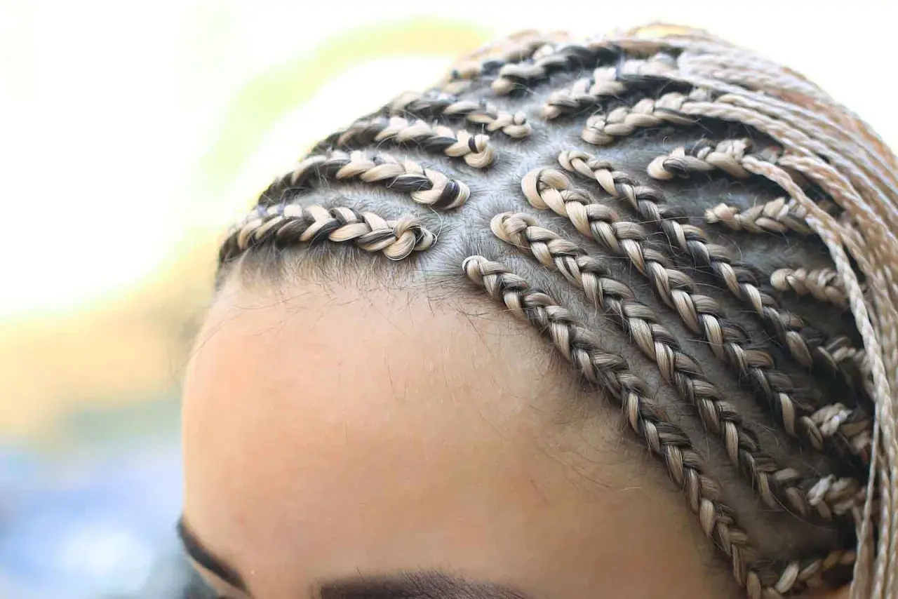 Primer plano de trenzas africanas rubias y castañas, peinado detallado y elegante.