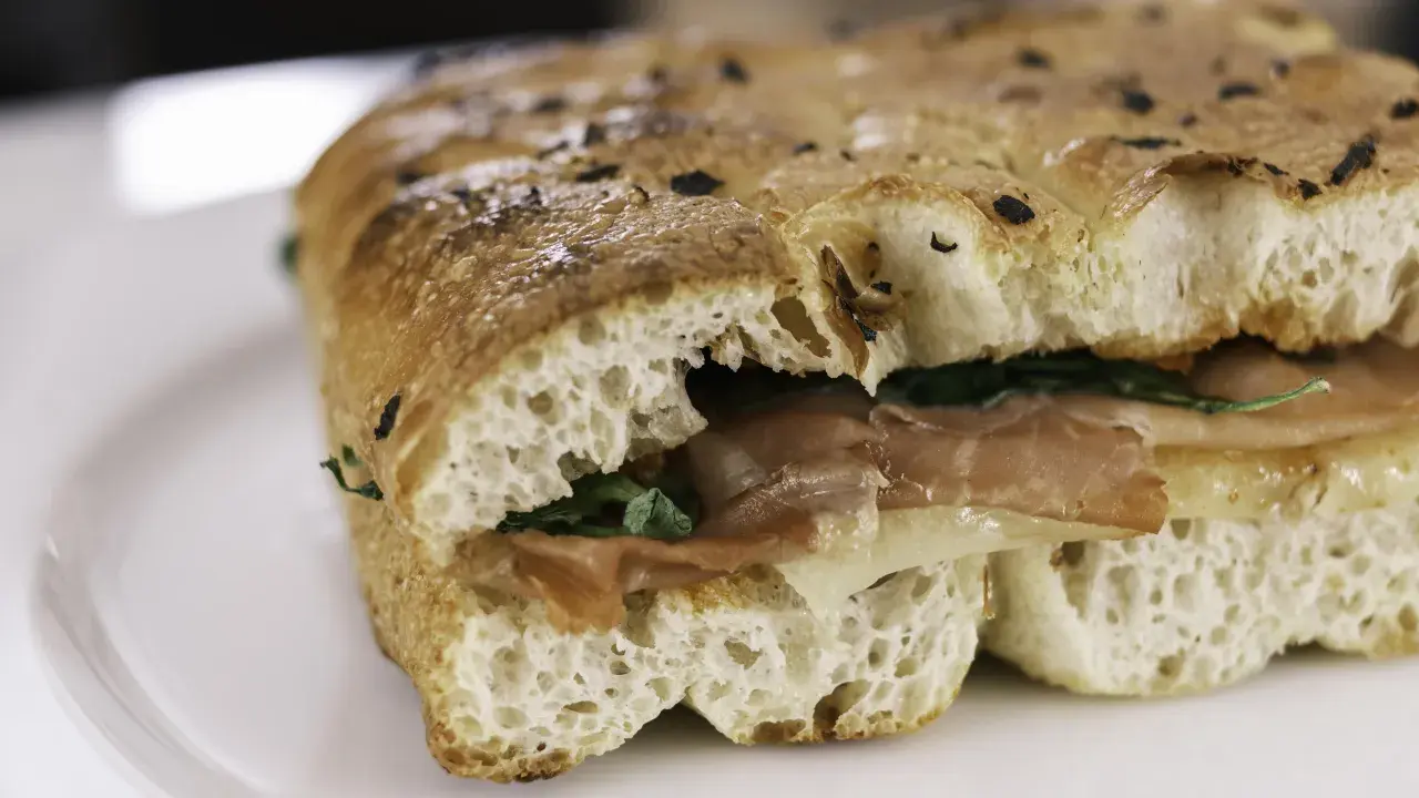 Un sandwich gourmand garni de jambon et de fromage, servi dans un pain italien moelleux et croustillant.