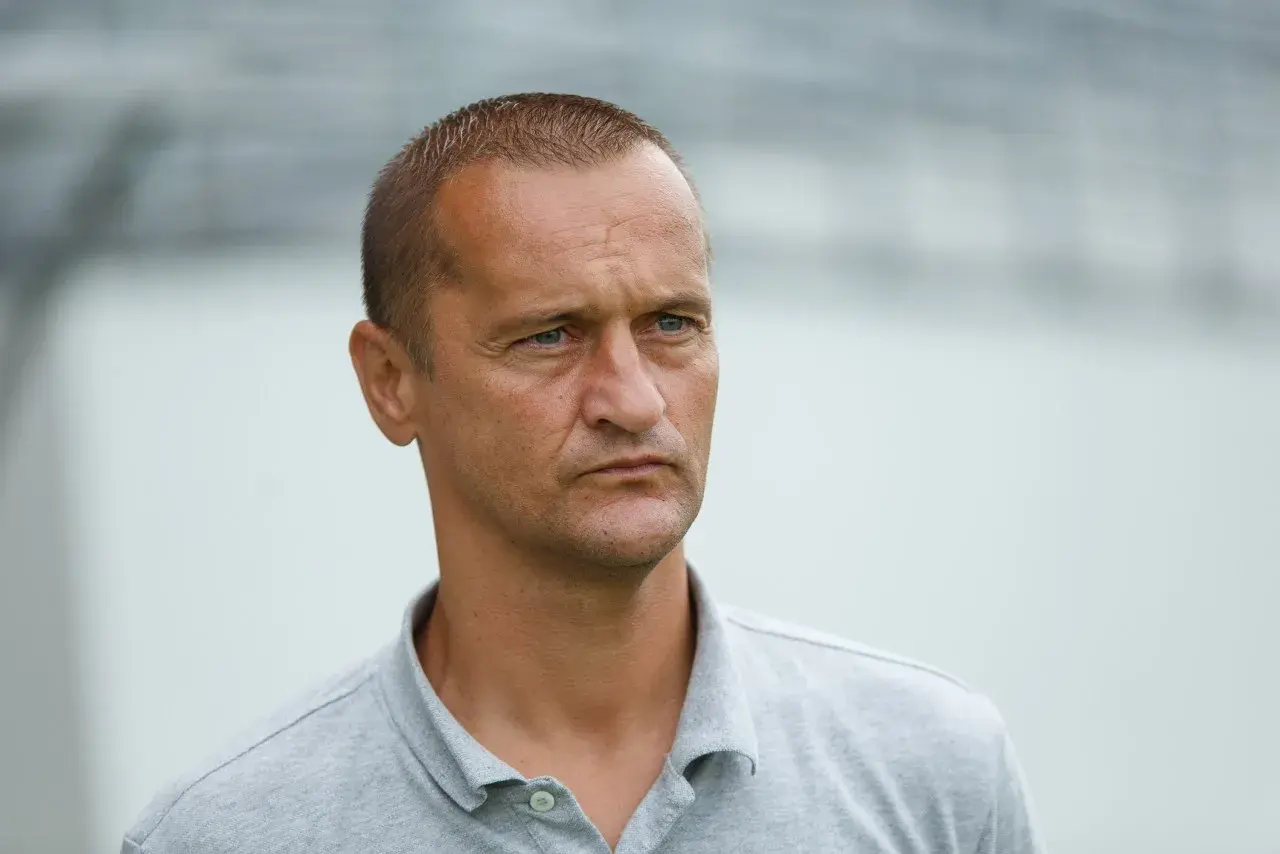 Dariusz Dźwigała w szarym polo, zamyślony, patrzy w bok.