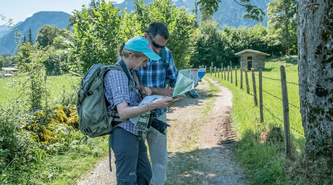 Zwei Wanderer mit Rucksäcken studieren eine Karte, um ihre Route zu planen. Die Packliste fürs Pilgern ist wichtig für die Tour.