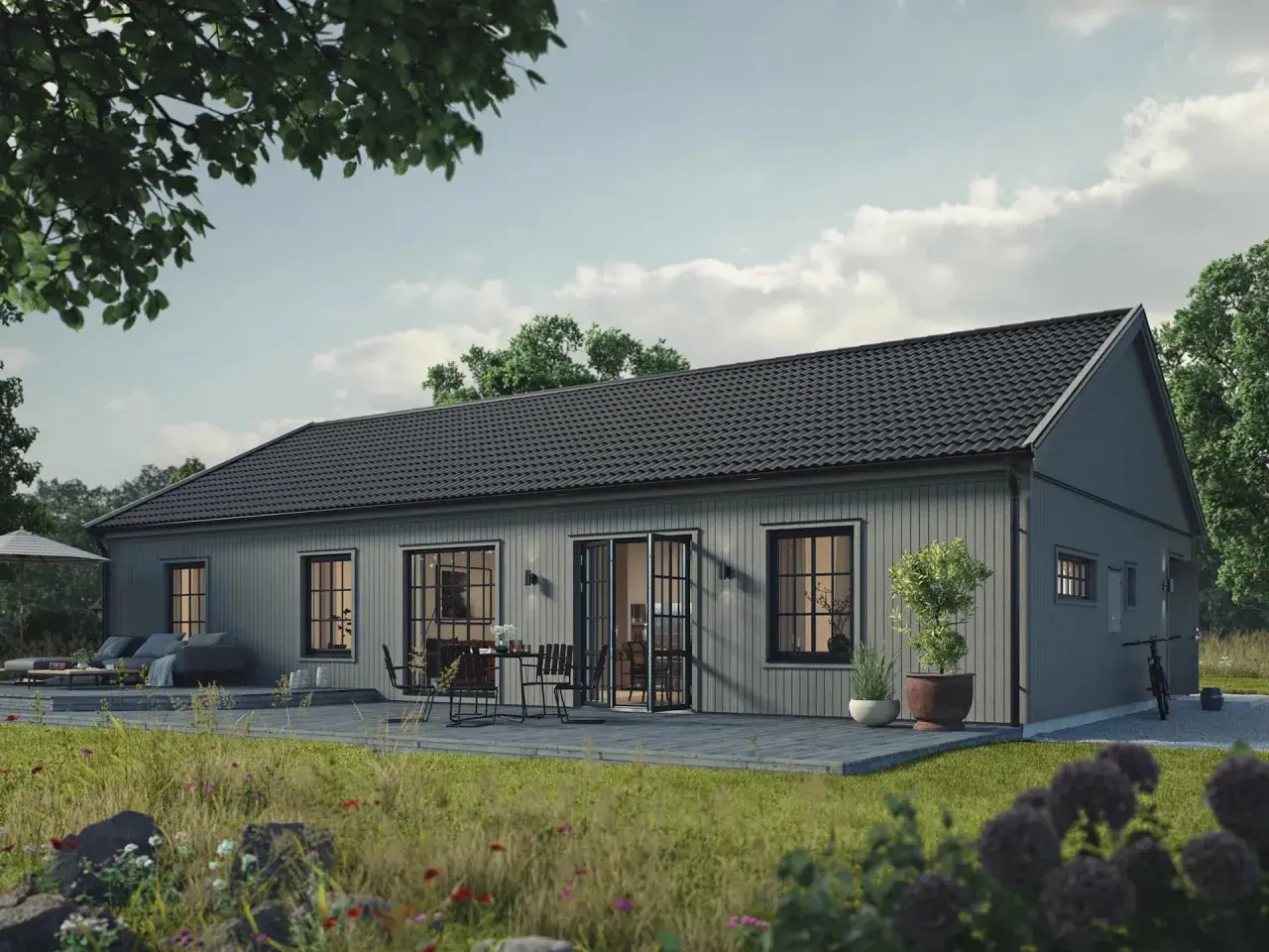 Grått trähus med altan och utemöbler. En cykel står parkerad. Tänk på vad kostar det att bygga ut huset för att få mer plats.