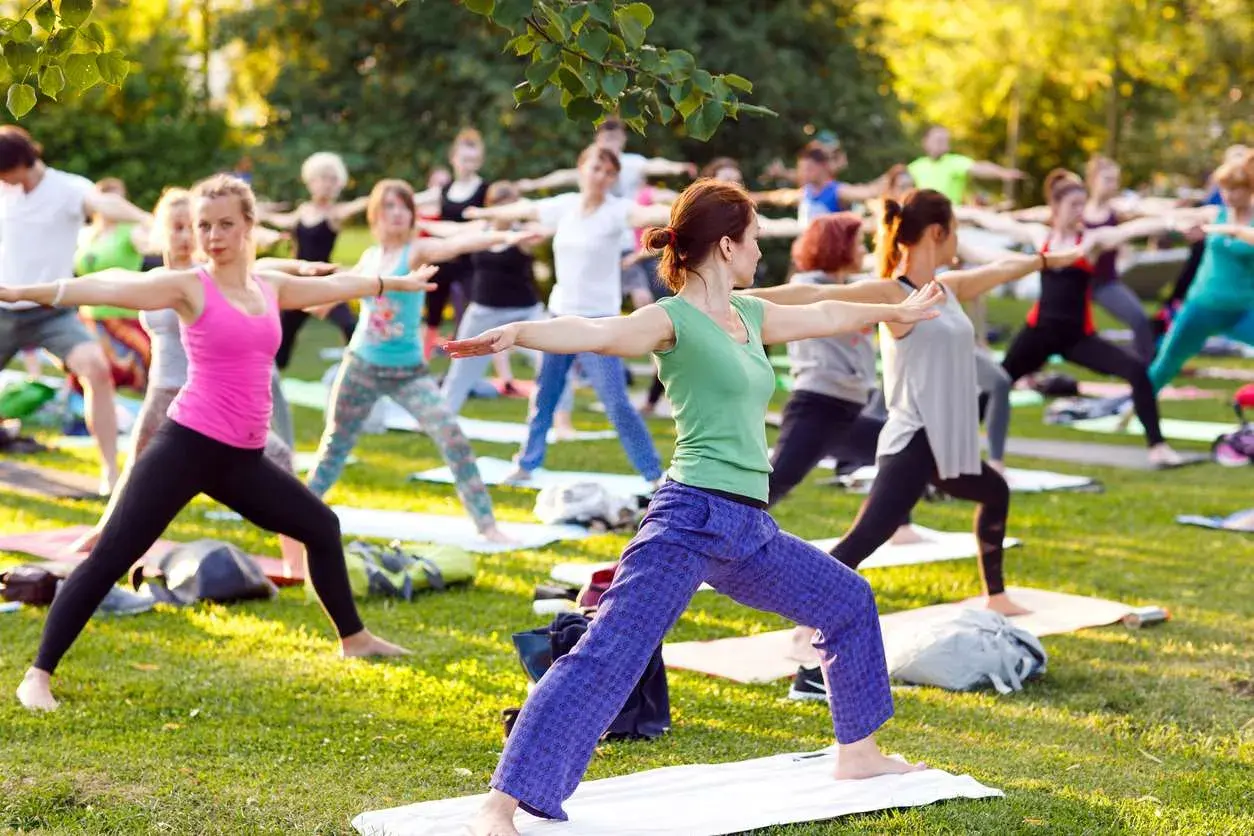 Un groupe de personnes pratique le yoga en plein air, profitant du soleil. Faire du yoga tous les jours apporte calme et équilibre.