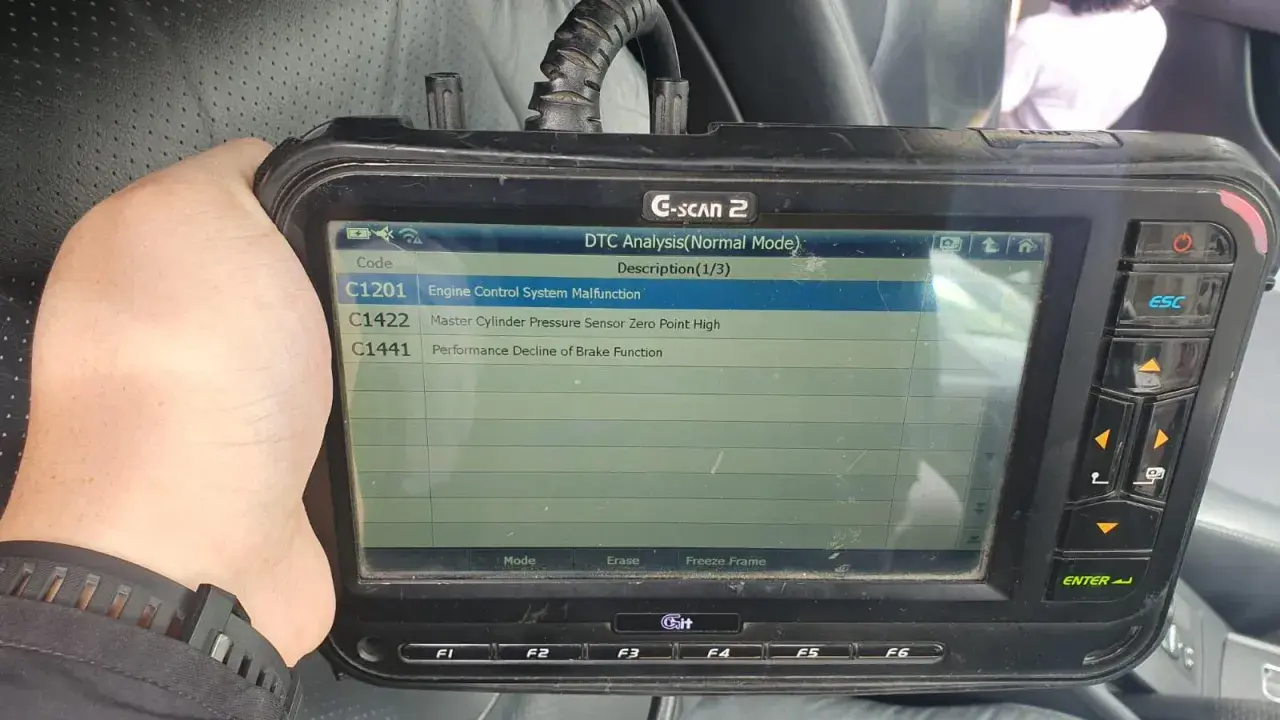 Escáner G-SCAN 2 muestra código C1201, fallo en sistema de control de motor de un Toyota.