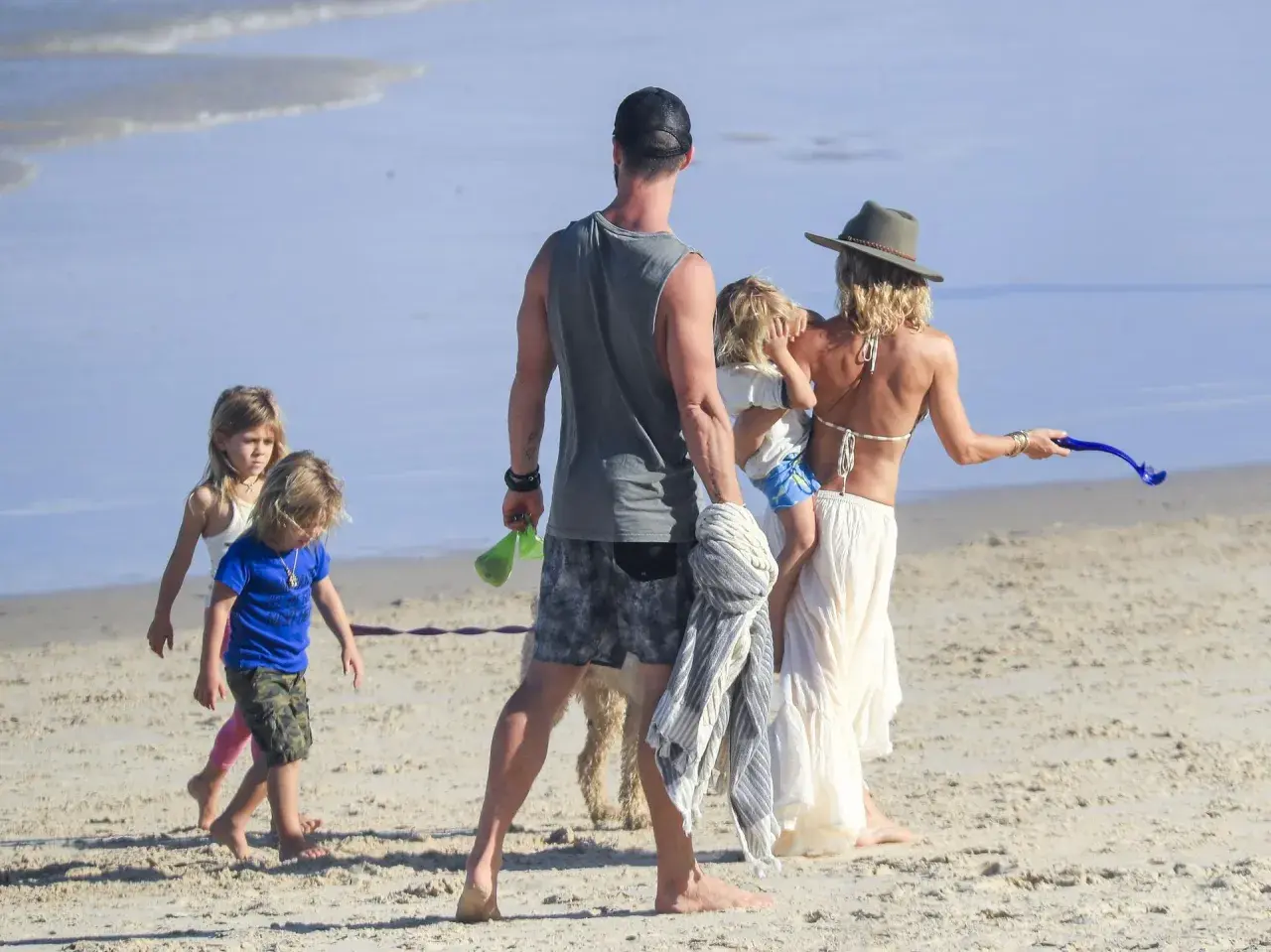 Chris Hemsworth z dziećmi i żoną na plaży. Rodzina cieszy się słońcem i piaskiem.