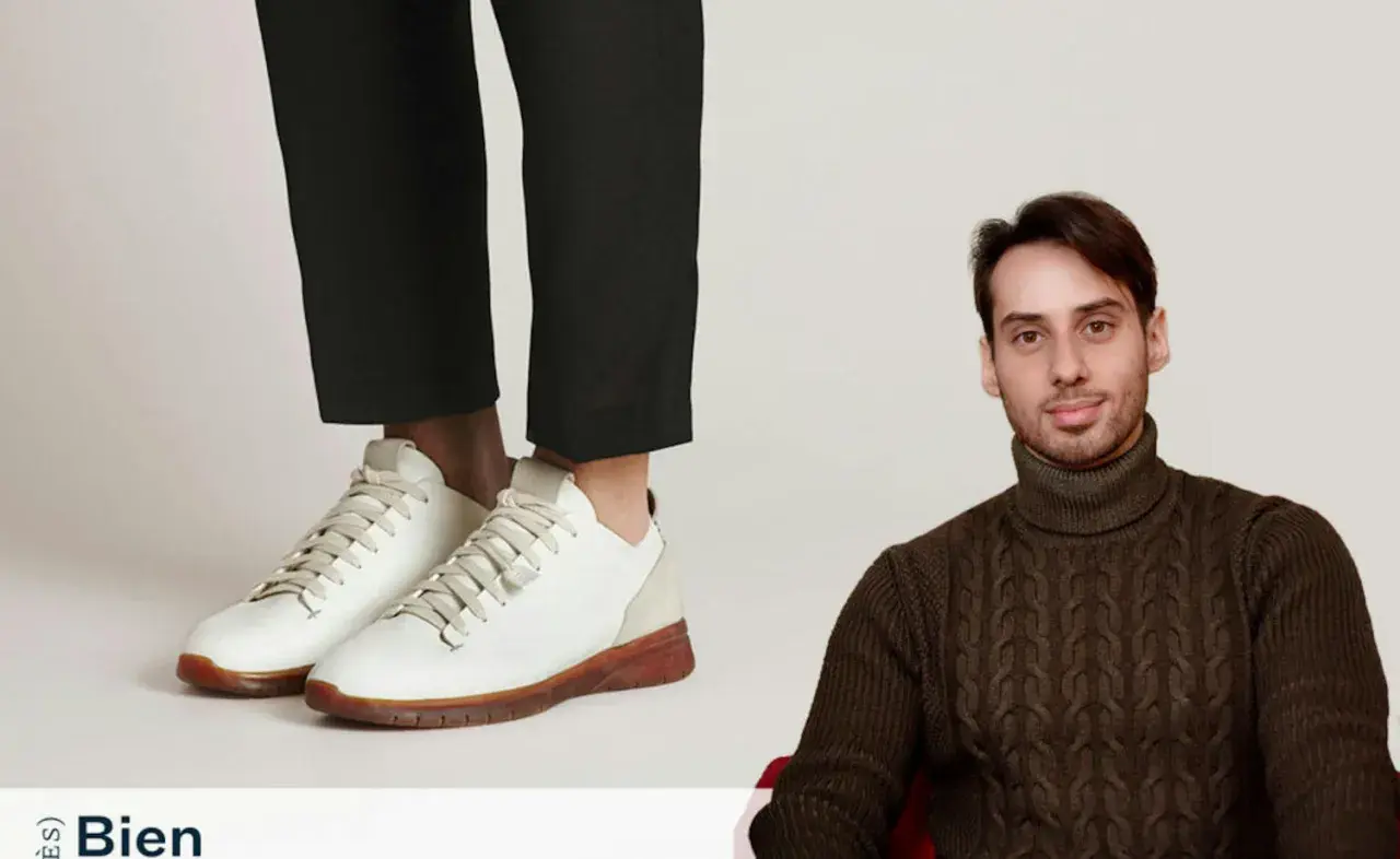 Un homme porte un pull à col roulé et un pantalon cigarette avec une chaussure blanche.