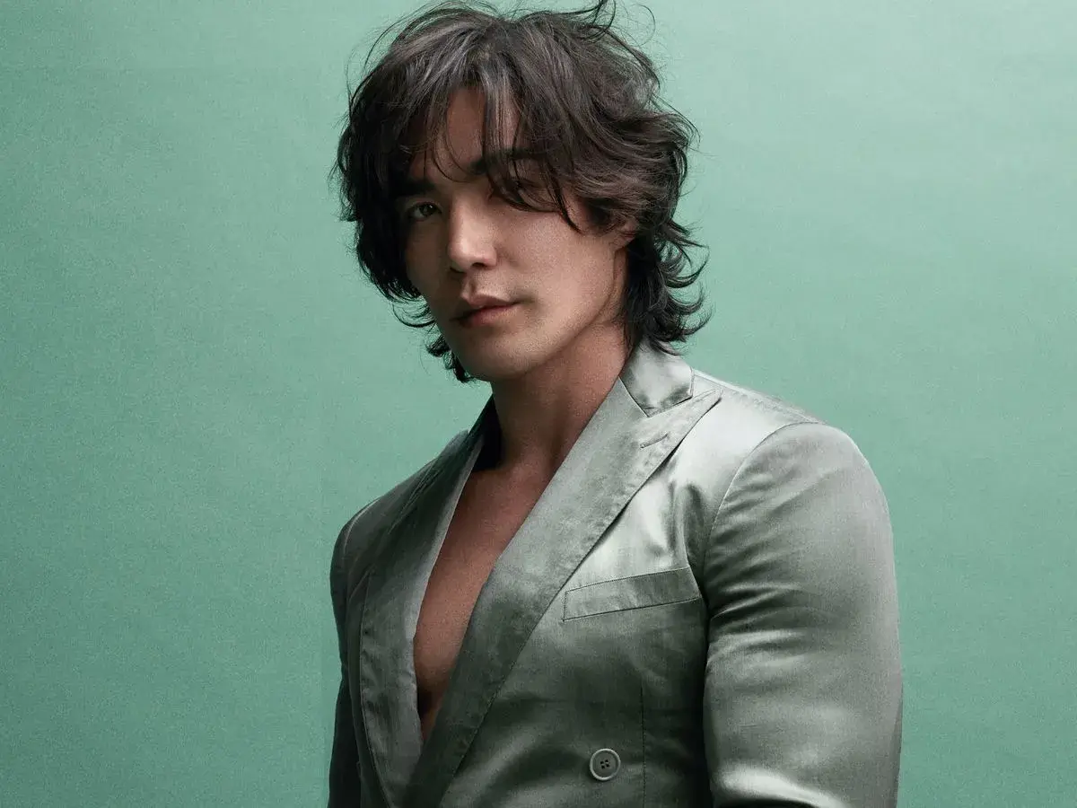 Ludi Lin, star de films et séries tv, pose dans un costume satiné sur fond vert menthe.