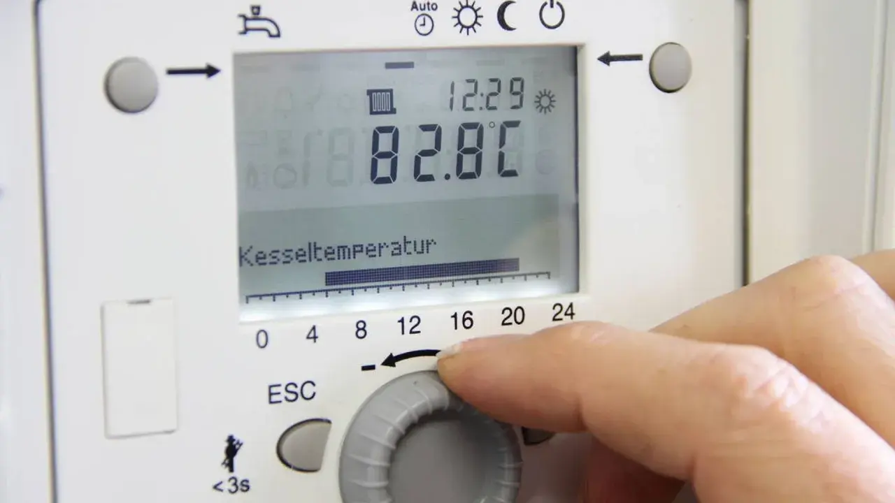 Hand stellt die vorlauftemperatur gasheizung ein. Kesseltemperatur 82.8°C.
