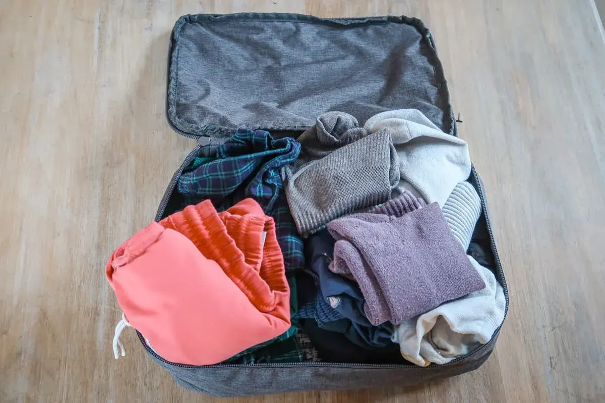 Packliste für Rucksackreisen: Kleidung wie kariertes Hemd, rote Shorts und Pullover sind wichtige Backpacking Must Haves.
