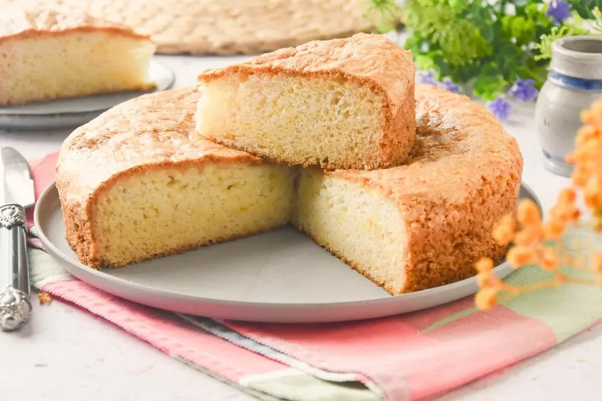 Bizcocho sin huevo esponjoso y dorado, servido en plato gris con servilleta colorida. Perfecto para un postre ligero.