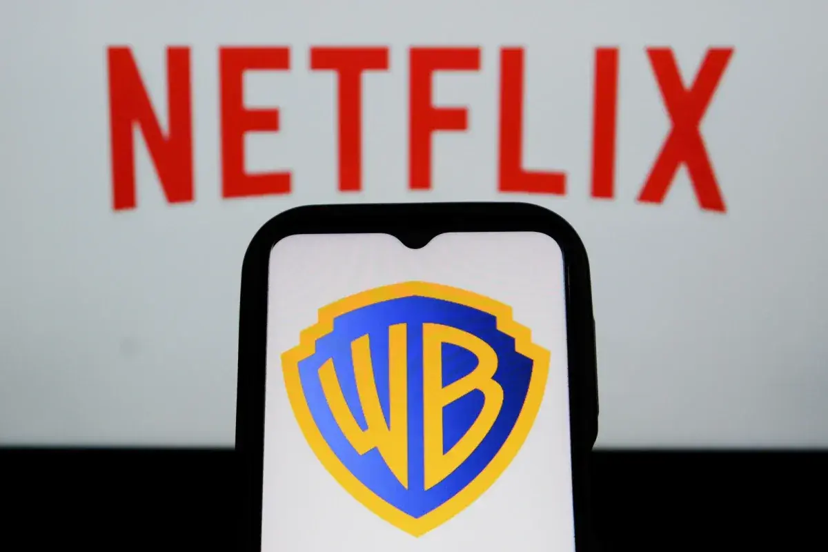 Logo Warner Bros. na ekranie telefonu, w tle napis Netflix. Analiza akcji WBD.