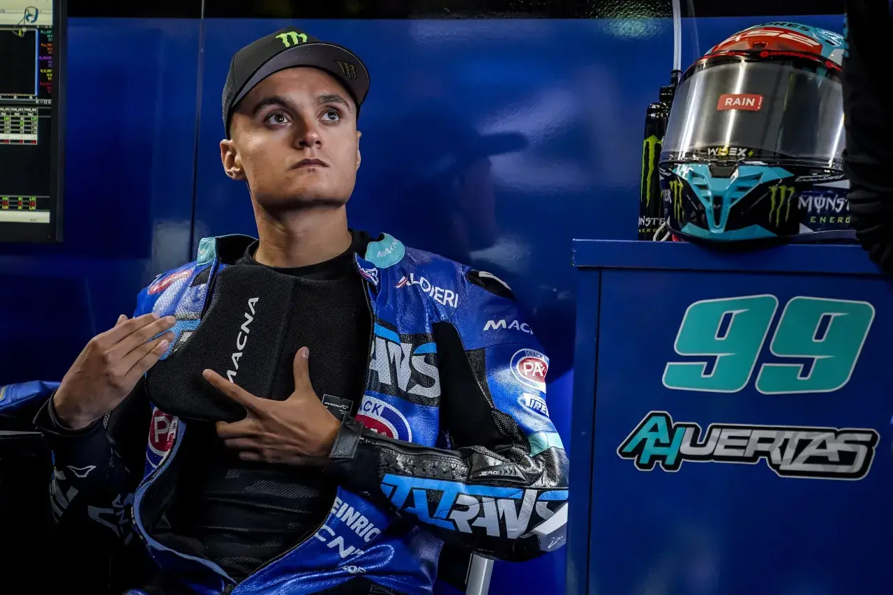 Adrian Huertas, piloto de motociclismo, con su casco y mono azul. El número 99 destaca en el fondo.