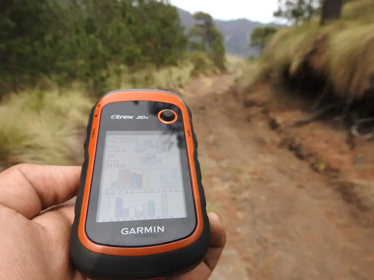 Ręka trzyma GPS Garmin Etrex 20x, idealny do poszukiwań w terenie. To właśnie dzięki takim urządzeniom odkrywasz, geocaching co to jest i jak działa.