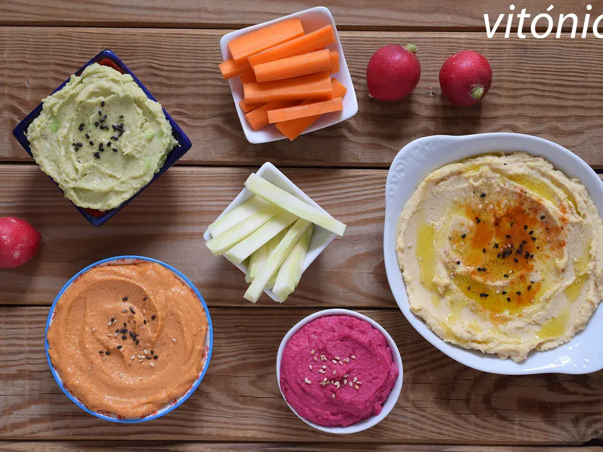 Variedad de hummus, zanahorias, apio y rábanos. Ideas para recetas de hummus saludables y deliciosas.