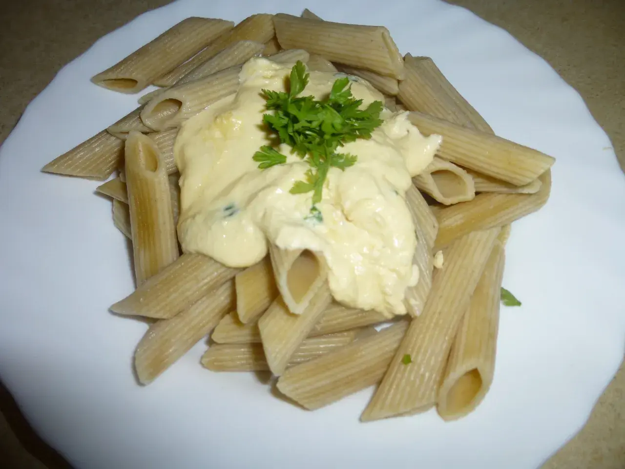 Penne z kremowym sosem pomidorowym z ricottą, udekorowane natką pietruszki. Pyszne danie gotowe w kilka minut.