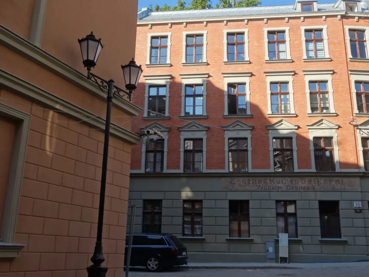 Urokliwe kamienice Gdańska z latarniami ulicznymi i ceglaną fasadą.